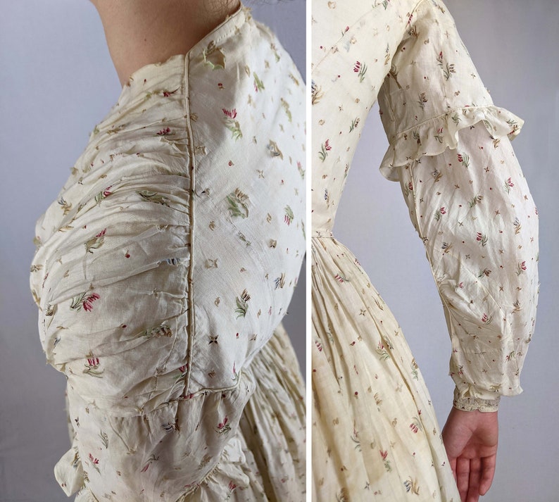 May include: A vintage white cotton dress with a floral print. The dress has a gathered bodice and long sleeves with ruffles at the cuffs.