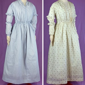 May include: Two long-sleeved dresses with a gathered waist. The dress on the left is light blue with a small floral pattern. The dress on the right is white with a small floral pattern.