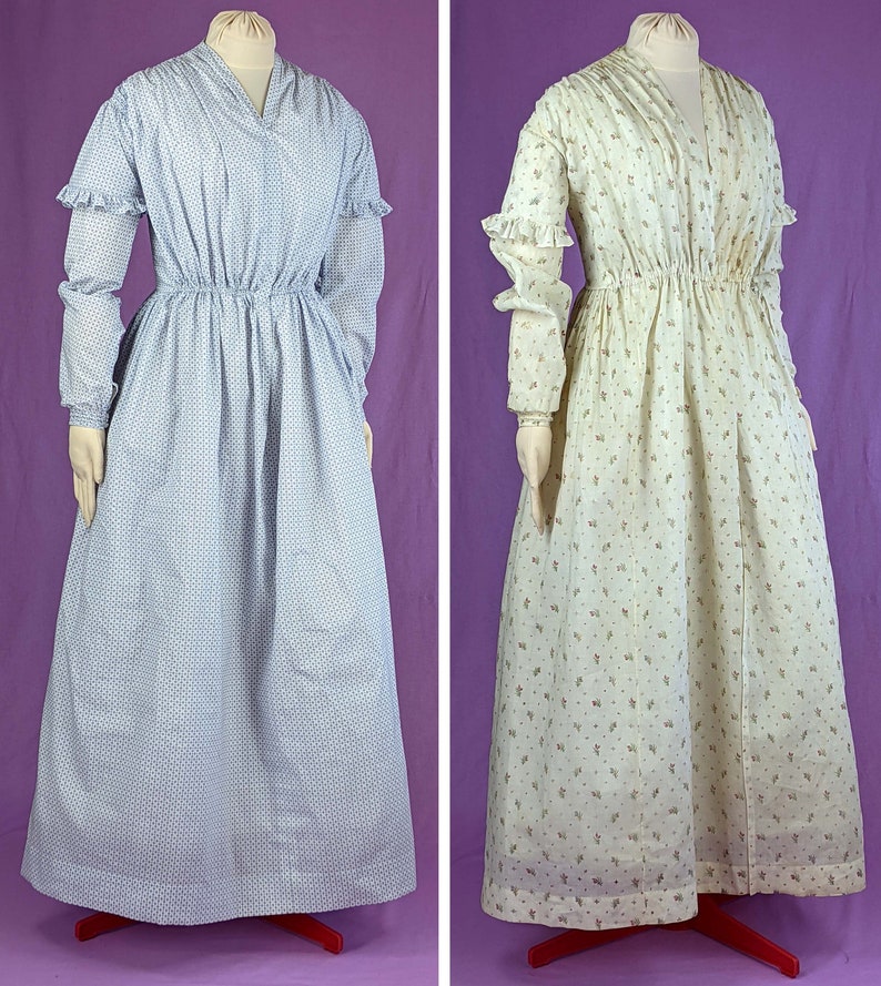 May include: Two long-sleeved dresses with a gathered waist. The dress on the left is light blue with a small floral pattern. The dress on the right is white with a small floral pattern.