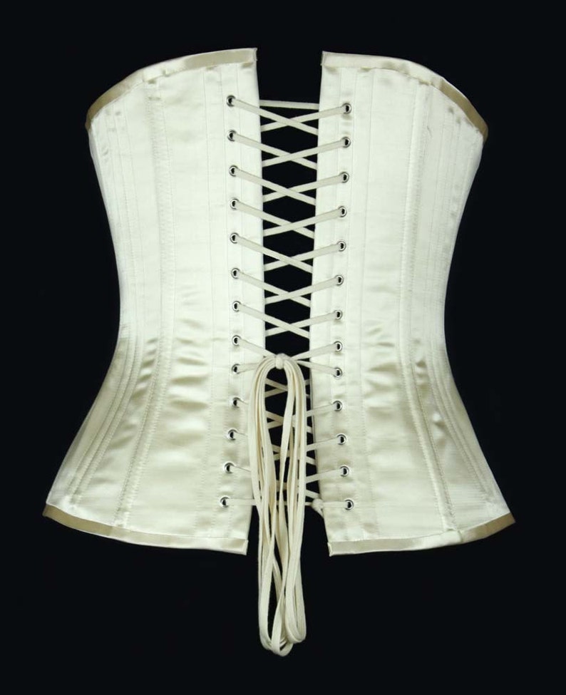 May include: A white satin corset with a lace-up back. The corset has a long, white ribbon tie at the bottom.