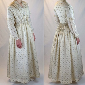 May include: A long-sleeved white dress with a floral print. The dress has a gathered waist and a full skirt.