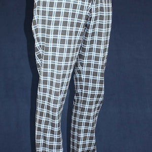 May include: Black and blue plaid pants with a button fly and suspenders. The pants are worn with black leather shoes.