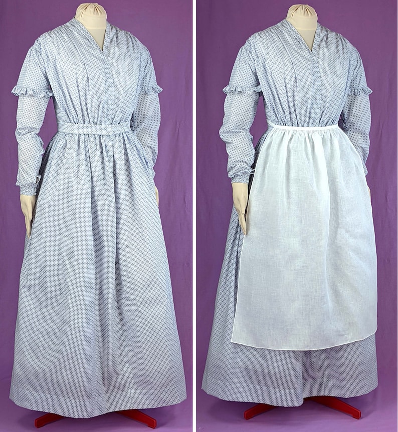 May include: A blue and white patterned dress with a white apron. The dress has a v-neck and long sleeves with ruffles at the cuffs. The apron is tied at the waist and hangs to the floor.
