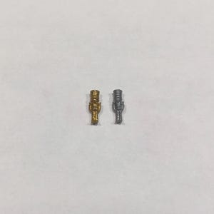 以下が含まれることがあります： 白い背景に、金色のミニチュアのナッツクラッカー人形と銀色のミニチュアのナッツクラッカー人形が並んでいます。