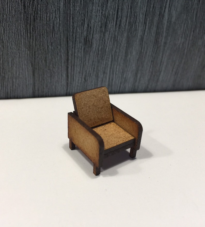 May include: A miniature wooden armchair with a brown finish. The chair has a simple design with a curved back and armrests.