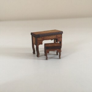 May include: A miniature wooden desk and chair set. The desk has a brown top and four legs. The chair has a brown seat and four legs.