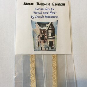 May include: A package of cream-colored lace trim for dollhouse curtains. The package includes a label that reads "Stewart Dollhouse Creations, Curtain lace for "French Book Nook" by Seaside Miniatures".