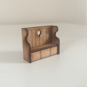 May include: A small wooden bench with a heart-shaped cutout in the back. The bench has a simple design and is made of light brown wood.