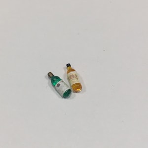 以下が含まれることがあります： 白い表面に置かれた、緑色のミニチュアガラス瓶と琥珀色のミニチュアガラス瓶の2本。瓶にはラベルが貼られています。