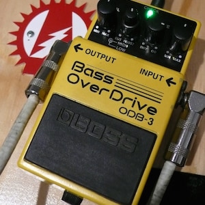 Op de afbeelding: Een gele Boss ODB-3 Bass OverDrive effectpedaal met zwarte knoppen en een zwarte voetschakelaar. De pedaal heeft een groen LED-lampje dat aangeeft wanneer het effect aan staat.
