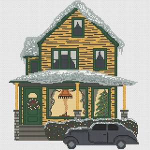 May include: A yellow house with green trim and snow on the roof. The house has a porch with a wreath on the door and a Christmas tree in the window. A black car is parked in front of the house.
