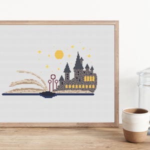 May include: A cross-stitch pattern featuring a gray castle with yellow windows, a yellow moon, and stars. The castle is on an open book with red wands.
