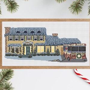 May include: A cross-stitch pattern of a yellow house with blue roof and snow on the roof, decorated with Christmas lights and a wreath on the front door. A red and white Christmas bus is parked in front of the house.