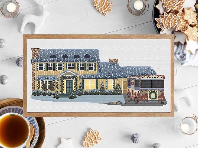 May include: A cross-stitch pattern of a yellow house with a blue roof and a red and white bus with a wreath on the side. The house is decorated with Christmas lights and a wreath on the door. The bus is decorated with Christmas lights and a wreath on the front. The scene is set against a white background.