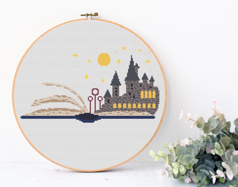 May include: A cross-stitch pattern of Hogwarts castle, a magical school from the Harry Potter series, emerging from an open book. The castle is depicted in gray and black with yellow windows, and the book is beige with a brown spine. The background is white with a yellow moon and stars.