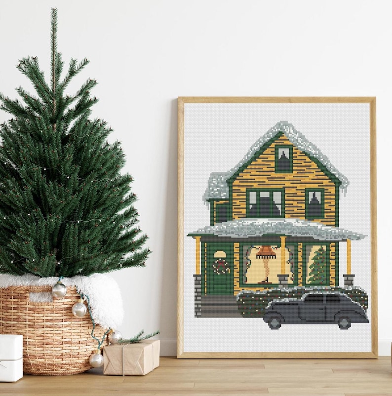 May include: A cross-stitch pattern of a yellow house with a green roof and a black car in front of it. The house has snow on the roof and a wreath on the door. The car has a license plate that says "Merry Christmas".