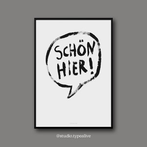 May include: Black and white print featuring a speech bubble that reads "SCHÖN HIER!" in a bold, handwritten style. The print is framed in a black frame.