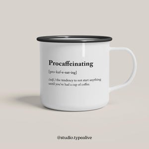 Puede incluir: Taza de esmalte blanco con borde y asa negros. La taza tiene texto negro que dice "Procaffeinating [pro-kaf-e-nat-ing] (adj.) the tendency to not start anything until you've had a cup of coffee." El texto también incluye el nombre de usuario de las redes sociales "@studio.typealive".