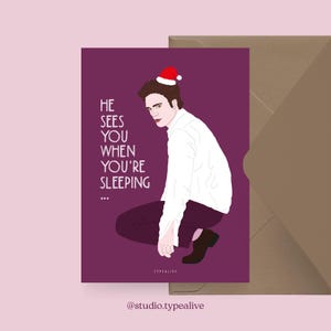 Könnte beinhalten: Eine Grußkarte mit lila Hintergrund und einer Illustration einer Person mit Weihnachtsmütze. Der Text auf der Karte lautet: "HE SEES YOU WHEN YOU'RE SLEEPING...". Ein brauner Umschlag liegt neben der Karte.