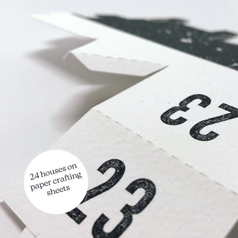 May include: Close-up of a paper craft advent calendar with the numbers 23 and 22 visible. The text "24 houses on paper crafting sheets" is visible in a circle.
