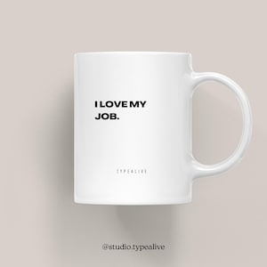 Może przedstawiać: Biały ceramiczny kubek z czarnym napisem "I LOVE MY JOB." i słowem "TYPEALIVE" poniżej. Kubek ma zakrzywiony uchwyt i jest umieszczony na neutralnym tle.