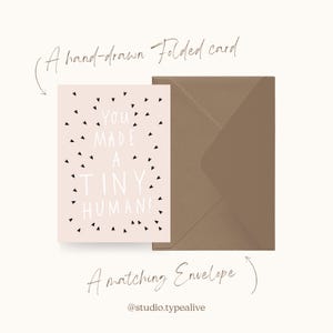 May include: A pink folded card with black hearts and the text "You made a tiny human!"  A brown envelope is included.