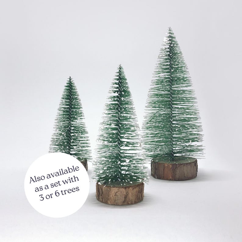 May include: Three miniature artificial Christmas trees with green flocked needles and brown wooden bases. Also available as a set with 3 or 6 trees.