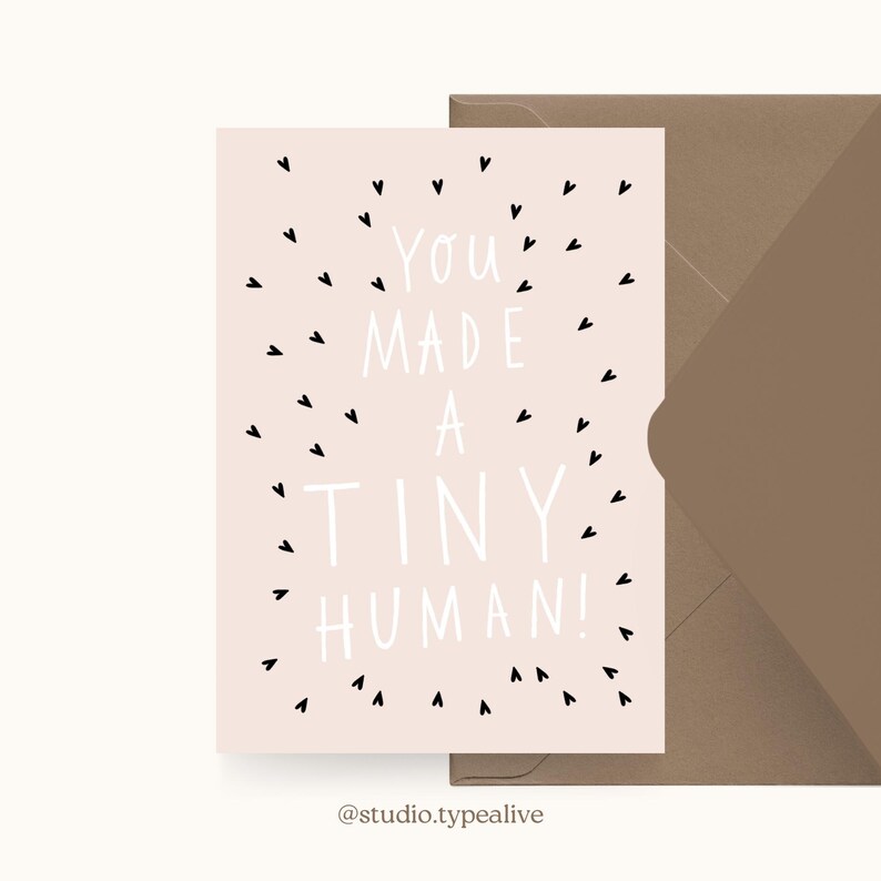 May include: A pink card with black hearts scattered around the text "You made a tiny human!"  The card is on a brown envelope.