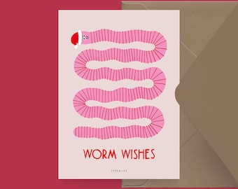 Op de afbeelding: Een wenskaart met een roze worm met een kerstmuts, met de woorden "WORM WISHES" in het rood. De kaart staat op een lichtroze achtergrond, met rechts een bruine envelop. De tekst "@studio.typealive" staat onderaan.