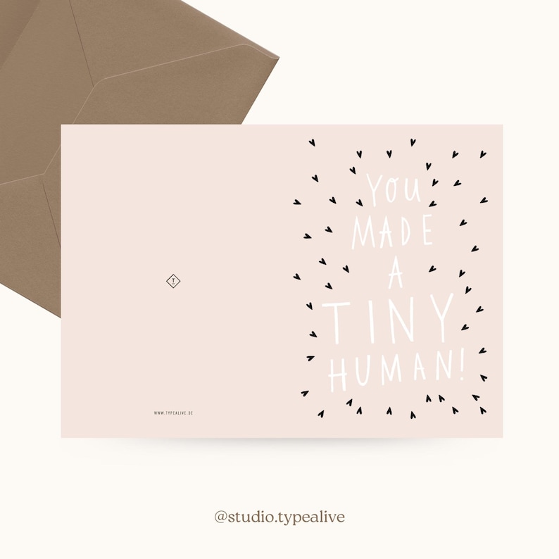 May include: A pink card with black hearts surrounding the text "You made a tiny human!" in white. The card is a new baby announcement.