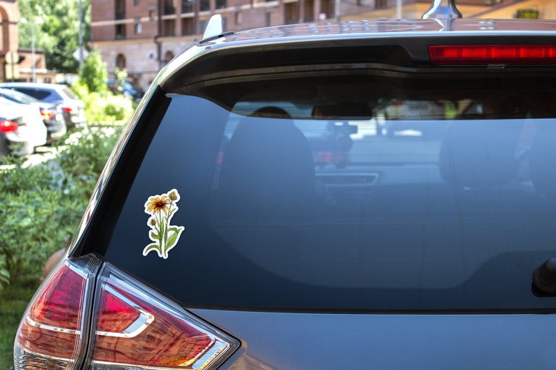 Puede incluir: Una pegatina para la ventana de un coche con una ilustraci&oacute;n de acuarela de una flor amarilla con hojas verdes.