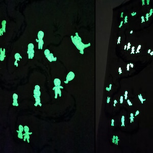 May include: Two dark panels with a black background, featuring glowing green figures. The figures are in various poses, resembling people and animals. The figures are scattered across the panels, creating a whimsical and artistic display.
