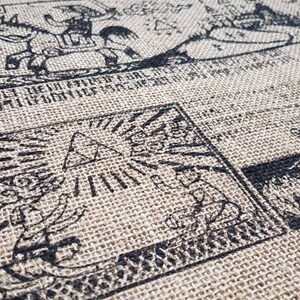 May include: A close-up of a brown burlap fabric with black ink drawings of various symbols and figures. The drawings include a triangle with rays of light, a figure riding a horse, and a group of figures standing in a line.