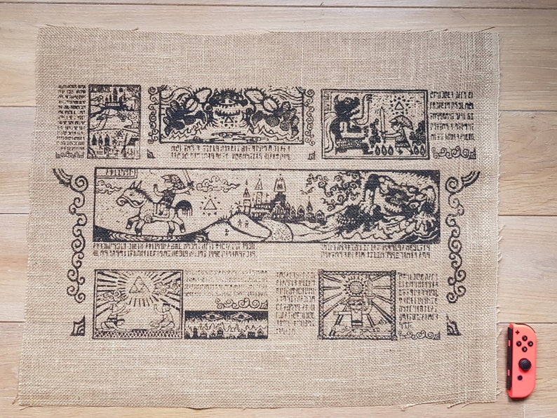 May include: A brown burlap fabric tapestry with black printed designs. The tapestry features a map with various symbols and text, including a sword, a castle, and a dragon. The tapestry is a decorative piece for a home or office.