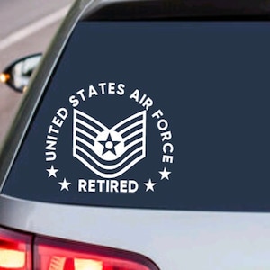 Peut inclure: Autocollant en vinyle blanc avec le texte "United States Air Force Retired" et un insigne de grade de l'armée de l'air stylisé. L'autocollant est sur la lunette arrière d'une voiture argentée.