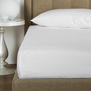 May include: A white fitted sheet on a bed with a brown headboard. The sheet is smooth and wrinkle-free.