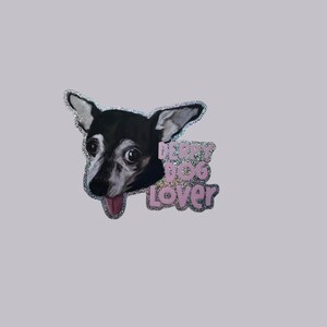May include: A sticker featuring a black and white dog with its tongue sticking out. The sticker has the text "Derpy Dog Lover" in pink, glittery letters. The dog has large eyes and a playful expression.
