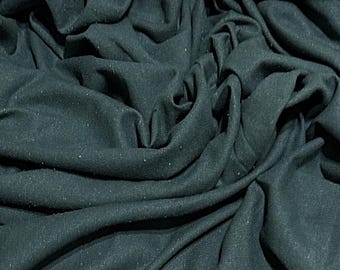 May include: Close-up of a dark teal fabric with a slightly textured surface. The fabric is folded and draped, creating soft folds and curves.