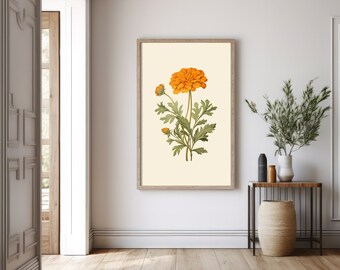 Puede incluir: Un estampado botánico enmarcado con una flor naranja y hojas verdes. La obra de arte está sobre un fondo crema y enmarcada en madera clara. La impresión se exhibe en una habitación luminosa con suelo de madera.