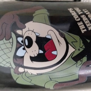 May include: A black and green mug featuring a cartoon character in a military hat and uniform. The text on the mug reads "The Corps Needs You Today".