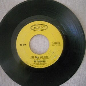 May include: A yellow vinyl record with black text that reads "45 RPM", "EPIC", "5-10094", "ZSP 116385", "THE NAZZ ARE BLUE", "THE YARDBIRDS", "Prod. by Paul Samwell-Smith & Simon Napier-Bell", "EPIC MARCAS REG. TM PRINTED IN USA".