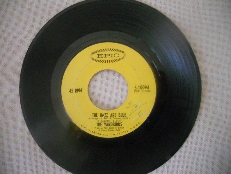 May include: A yellow vinyl record with black text that reads "45 RPM", "EPIC", "5-10094", "ZSP 116385", "THE NAZZ ARE BLUE", "THE YARDBIRDS", "Prod. by Paul Samwell-Smith & Simon Napier-Bell", "EPIC MARCAS REG. TM PRINTED IN USA".