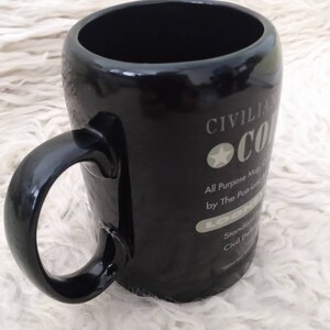 May include: Black ceramic mug with a white design that says "Civilian Coffee All Purpose Mug by The Patriotic Loon Standard Civil Defence"