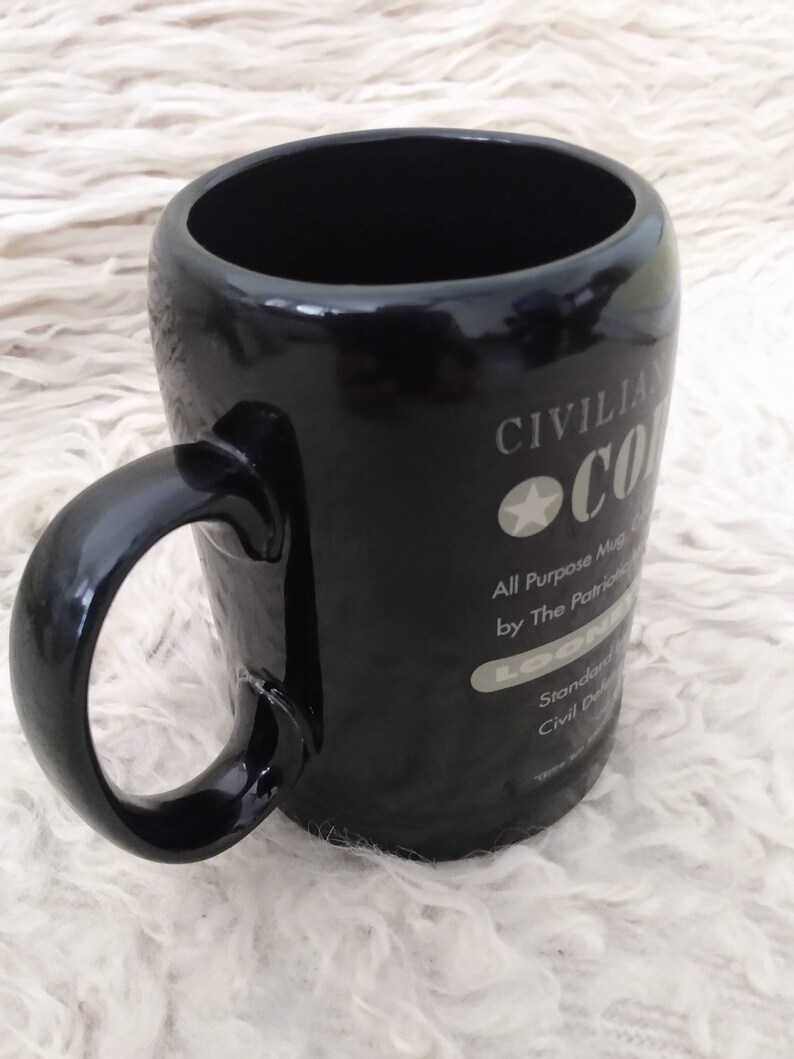 May include: Black ceramic mug with a white design that says "Civilian Coffee All Purpose Mug by The Patriotic Loon Standard Civil Defence"