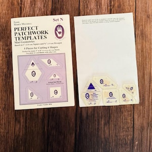 May include: A white ceramic mug with a black handle and the text "But First, Coffee" in a bold, black font. The mug is set against a blurred background, suggesting a cozy setting.