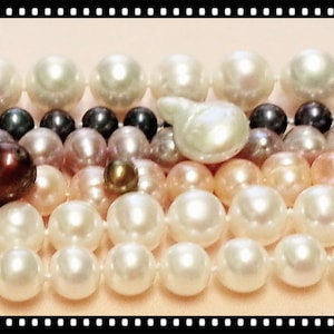 May include: A collection of multi-strand pearl necklaces featuring various sizes and shapes of pearls in shades of white, cream, soft pink, and dark charcoal. The strands are arranged horizontally, showcasing round and irregular baroque pearls.