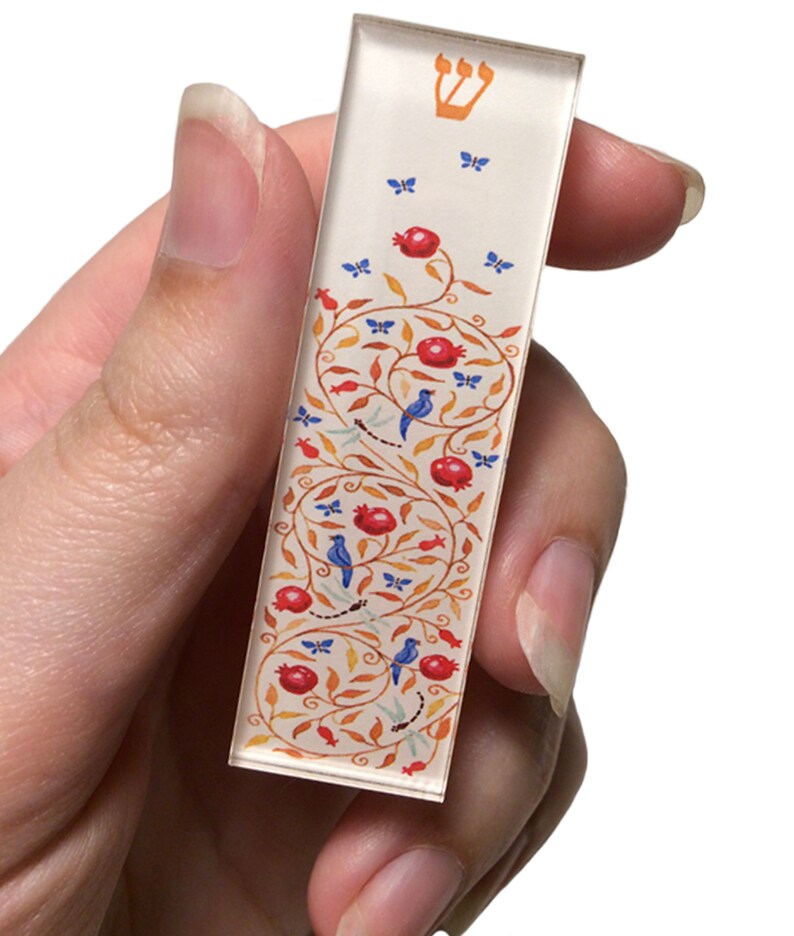 Puede incluir: Una mezuz&aacute; blanca con una estrella de David dorada en la parte superior. La mezuz&aacute; est&aacute; decorada con un dise&ntilde;o floral rojo y naranja con p&aacute;jaros azules y mariposas.