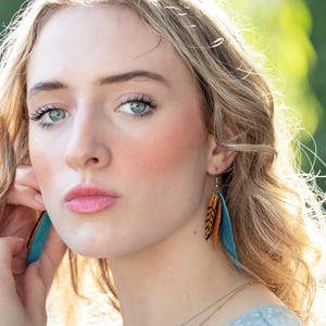 Model wearing feather earrings.