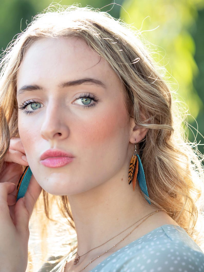 Model wearing feather earrings.