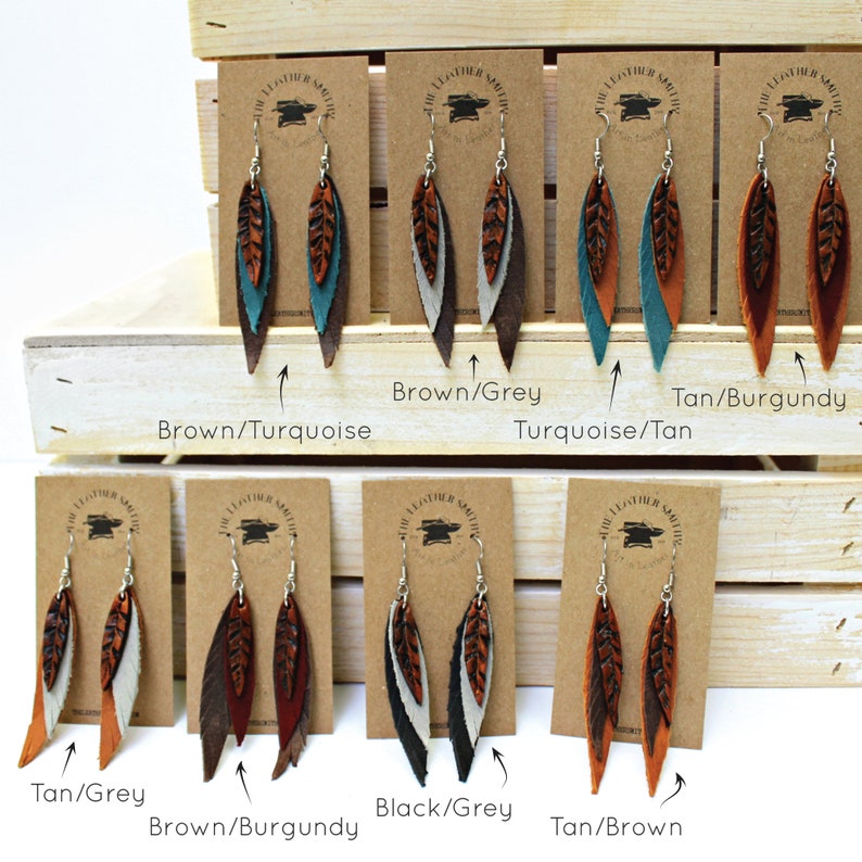 May include: Six pairs of leather earrings with a feather design. Each pair features two layers of leather in different colors. The colors include brown, tan, turquoise, burgundy, grey, and black.